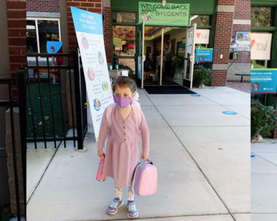 A student standing in front of a school.