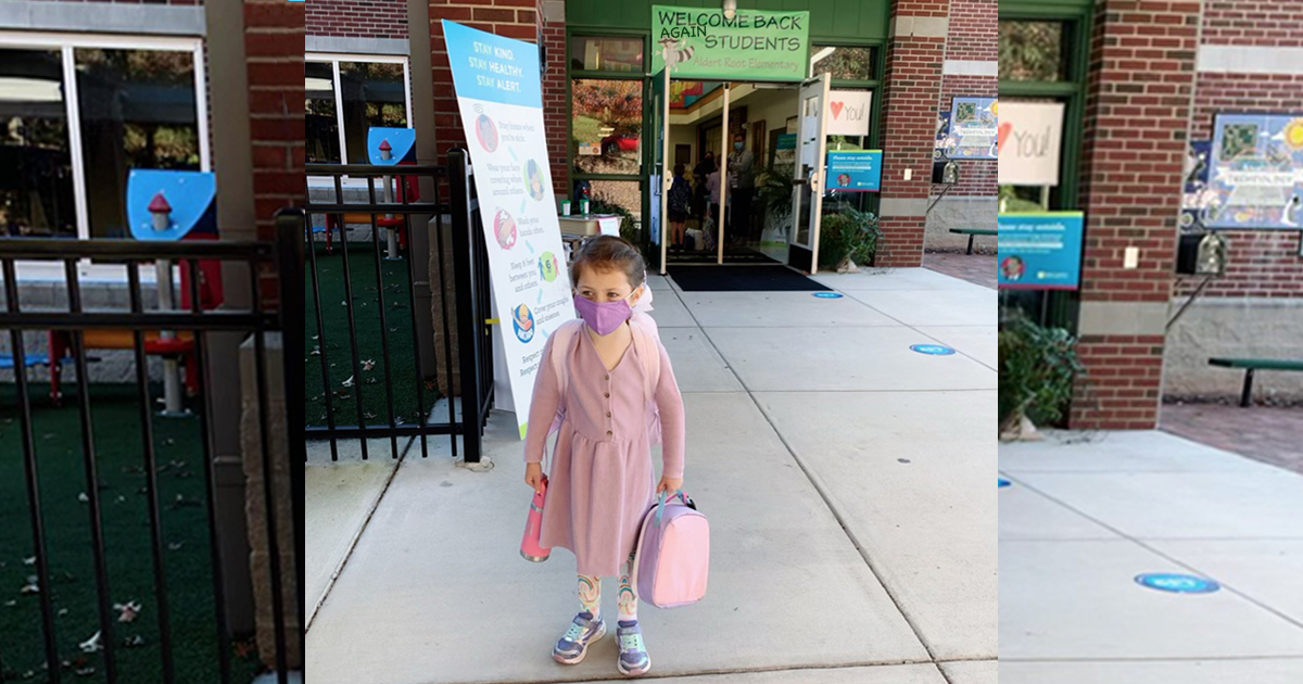 A student standing in front of a school.